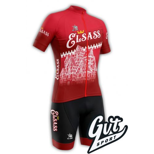 La photo représente la tenue cycliste Gvt Sport Elsass Cyclo comprenant un maillot cycliste de couleur rouge et un cuissard cycliste de couleur noir. 
Sur le devant, une illustration blanche et détaillée montre des maisons à colombages traditionnelles al